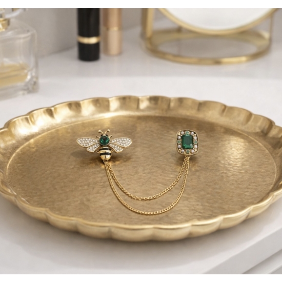 Broszka z motywem owada i zielonym kamieniem – elegancki detal, który podkreśla stylizację.