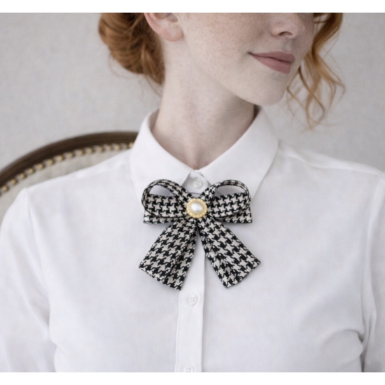 Elegancka broszka w formie kokardy w klasyczny wzór pepitki, wykończona perłowym środkiem – ponadczasowy dodatek do stylowych stylizacji.