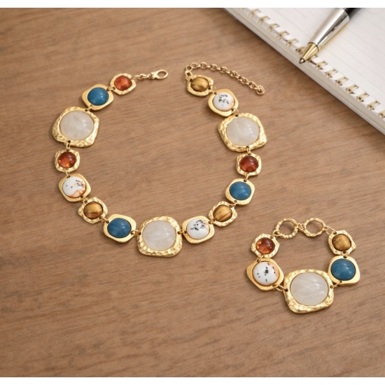 Elegancki komplet biżuterii w złotym odcieniu z dekoracyjnymi kamieniami – naszyjnik i bransoletka.