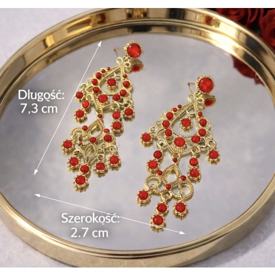 Eleganckie, długie kolczyki w złotym kolorze z czerwonymi kamieniami – biżuteria w stylu glamour, która przyciąga spojrzenia.