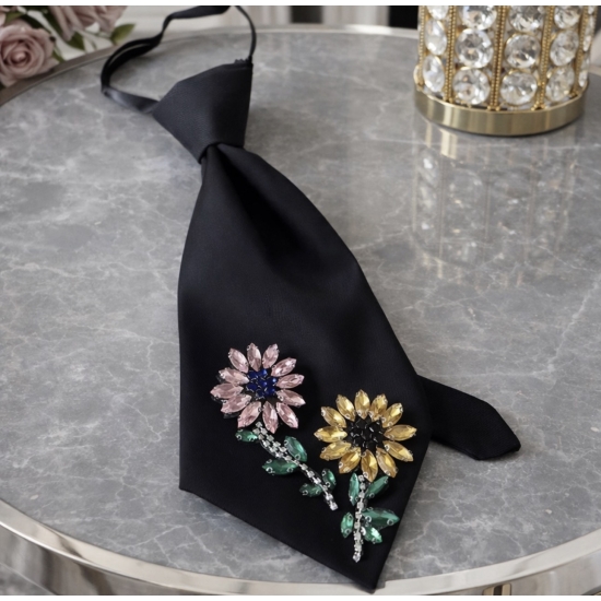 Czarny krawat z kwiatową aplikacją – biżuteryjny akcent stylizacji.
