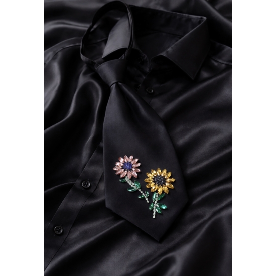 Czarny krawat z kwiatową aplikacją – biżuteryjny akcent stylizacji.
