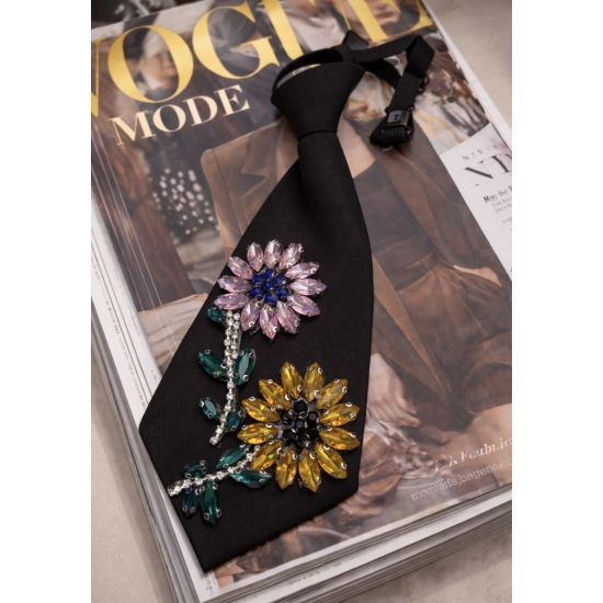 Czarny krawat z kwiatową aplikacją – biżuteryjny akcent stylizacji.